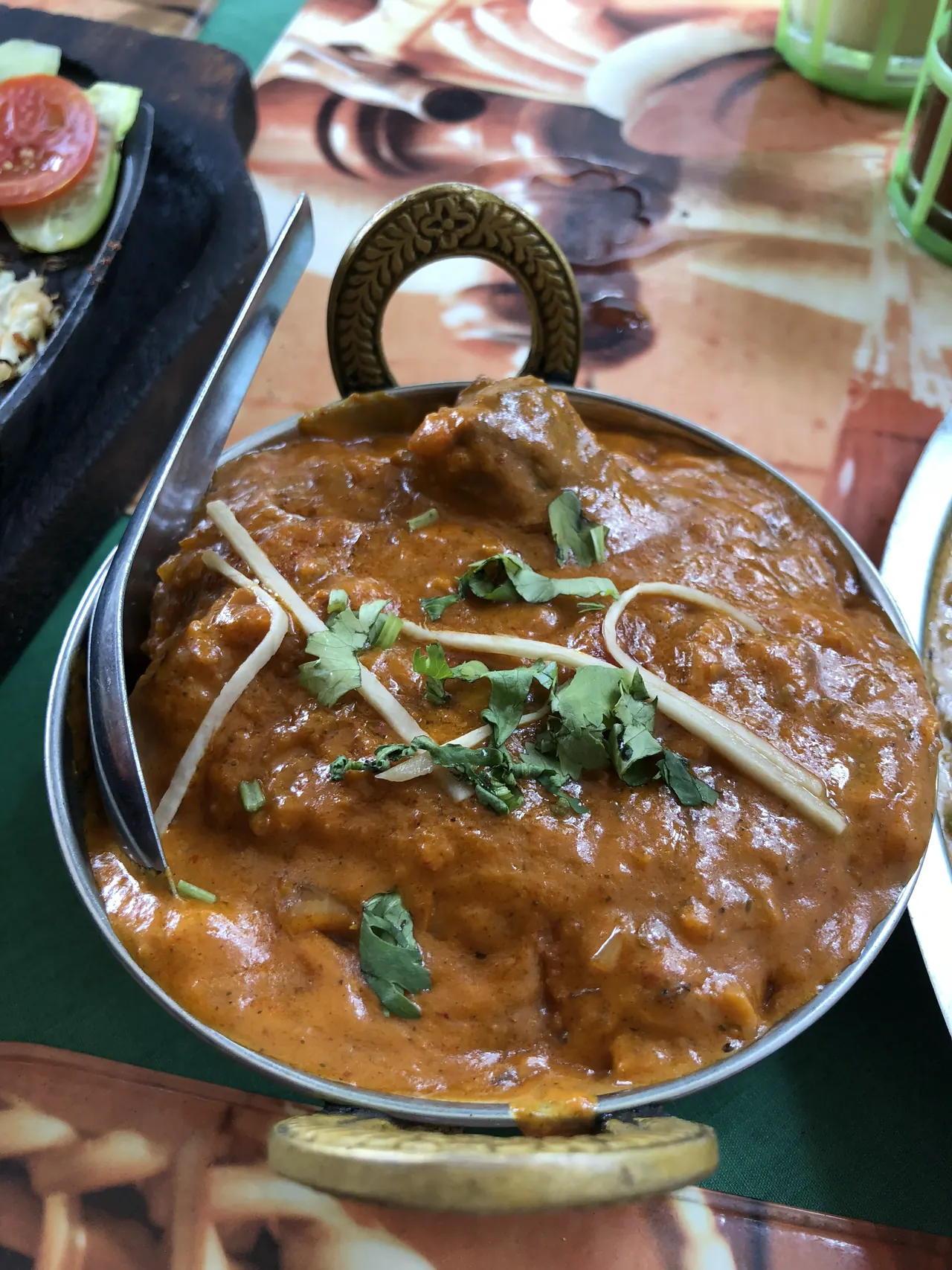 A rich brown curry with ginger and coriander in a brass karahi