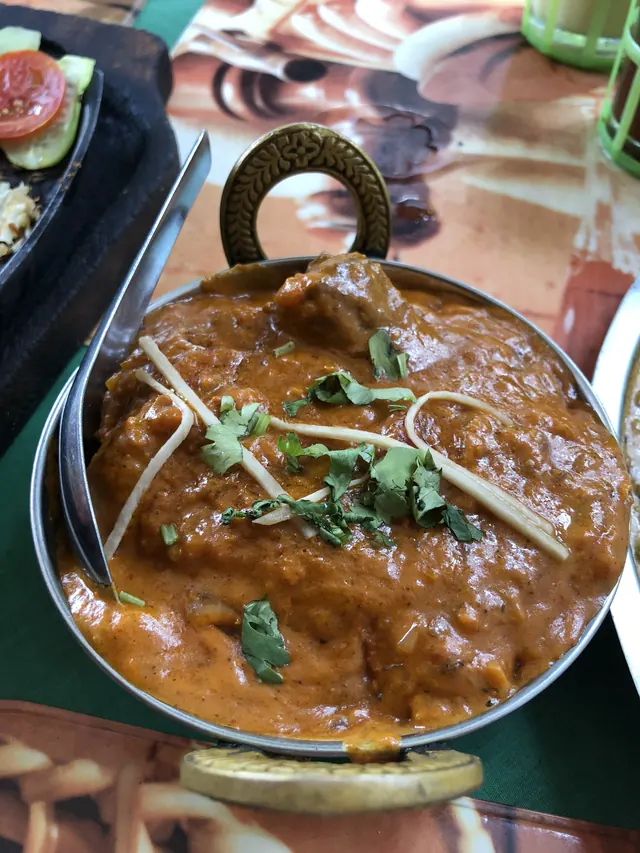 A rich brown curry with ginger and coriander in a brass karahi