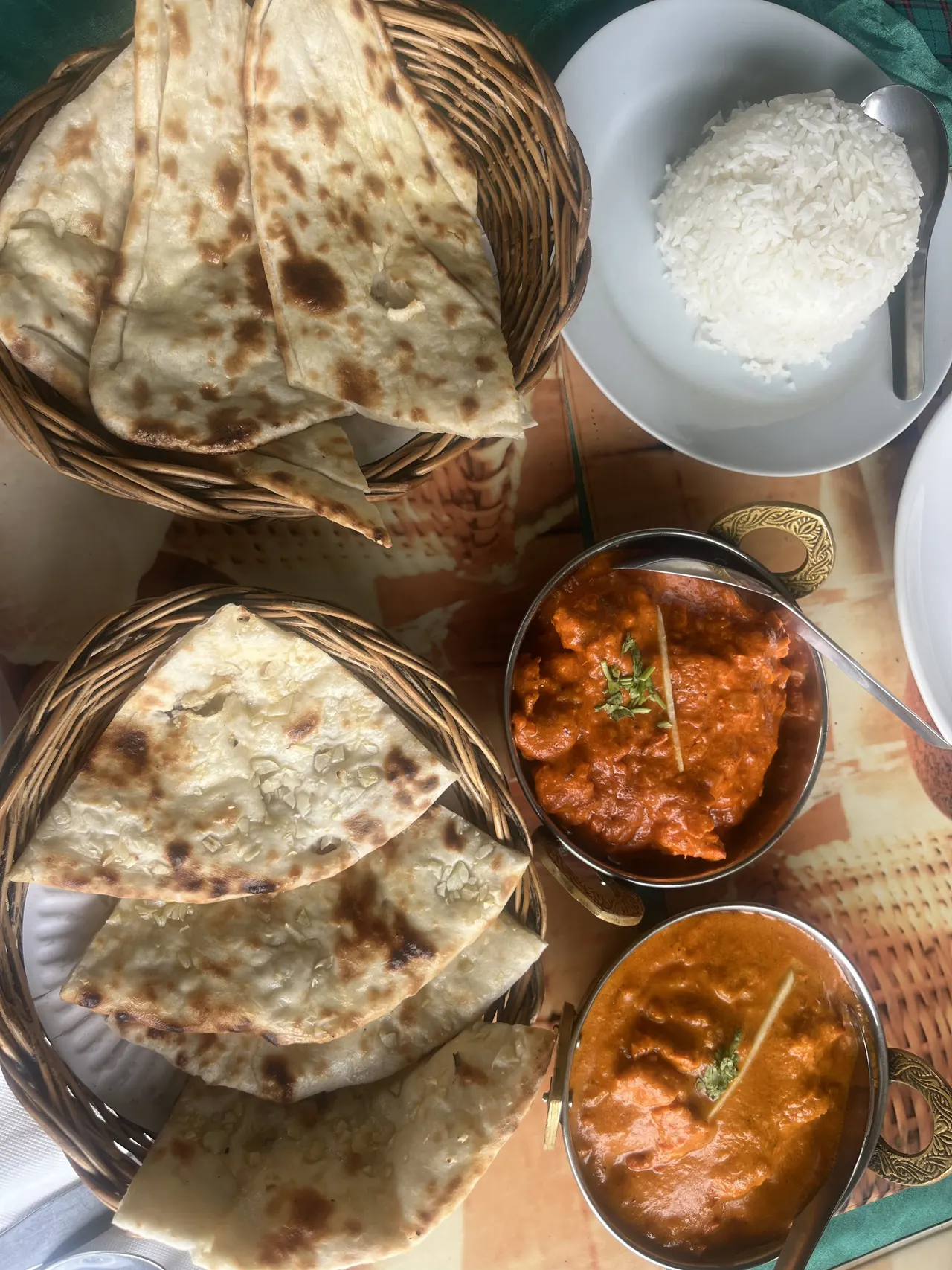 Baskets of naan with two curries and a bowl of rice