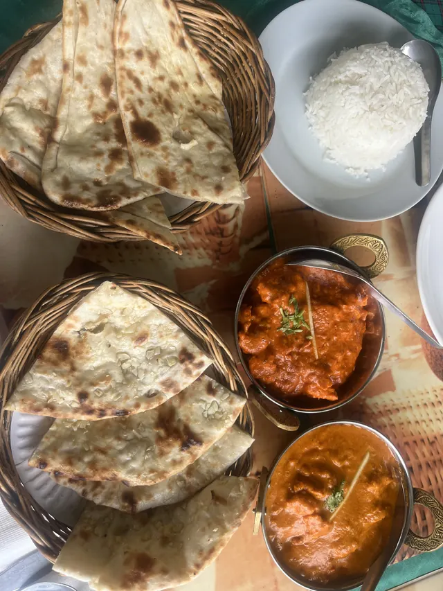 Baskets of naan with two curries and a bowl of rice