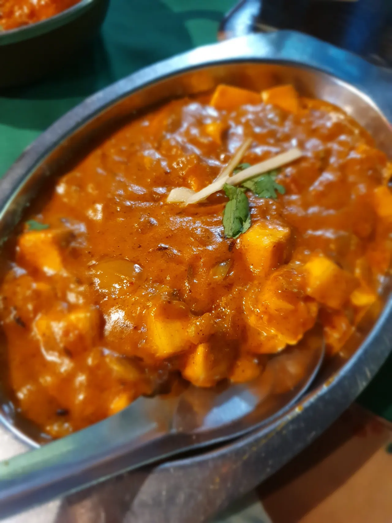Paneer in an orange masala sauce, topped with ginger and coriander