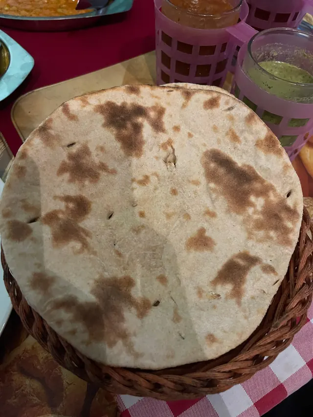A round, charred roti in a basket