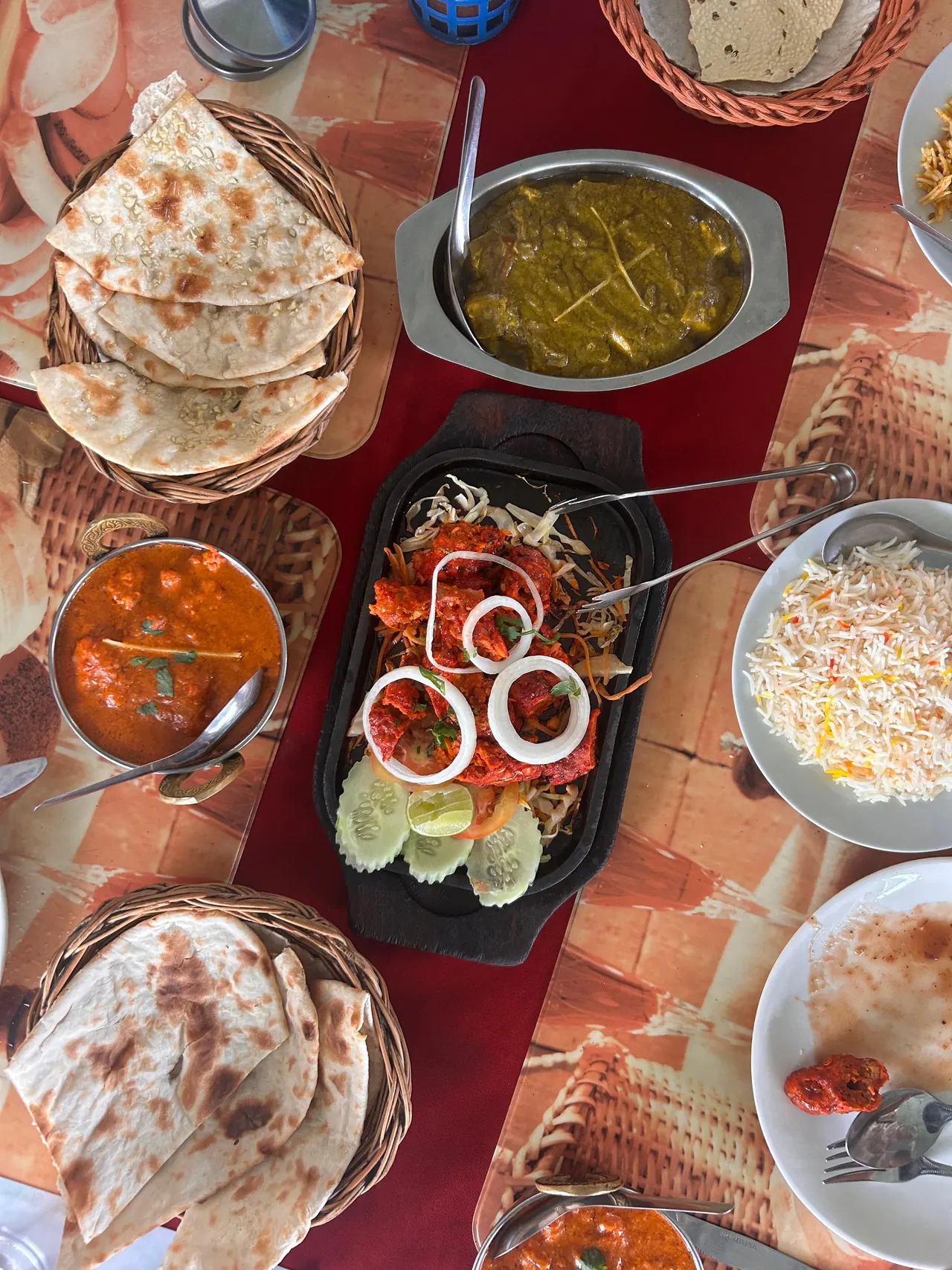 From above: naan, a sizzling platter, curries and rice on a red runner