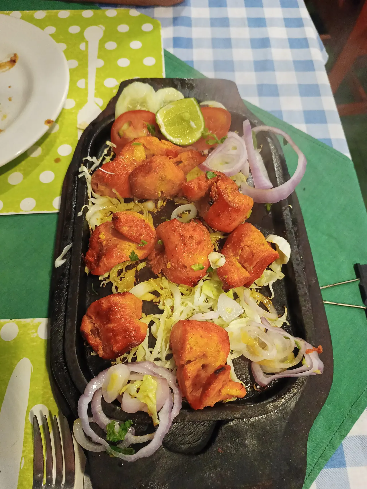Tikka on a cast-iron sizzler with onion, cabbage and lime