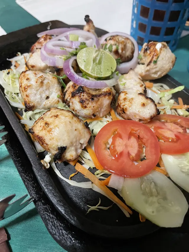 Tikka on a cast-iron sizzler with salad and lime